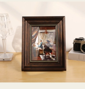 Close-up of vintage dark wood photo frame with golden rivets and artistic oil painting