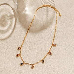 Detail of 18K gold plated necklace with colorful square zircon stones on beige background