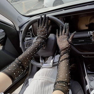 Close-up of black long tulle gloves with rhinestones on a driver holding a steering wheel