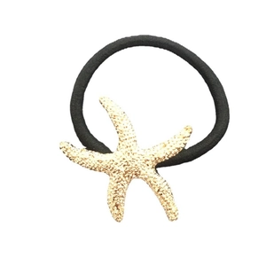 Golden starfish hair tie with metallic texture and black elastic band for beach styling