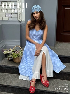 Blue plaid layered dress styled with crochet hat and red floral sandals on stone steps