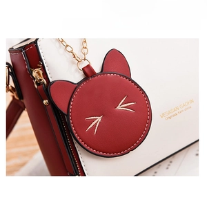 Detailed close-up of a red cat charm with gold embroidery on a leather handbag