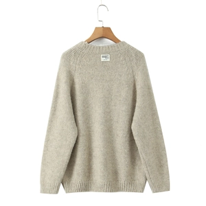 Detail of oatmeal crewneck knit sweater showing ribbed neckline and designer woven label