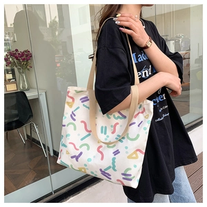 Close-up of cream canvas tote bag featuring colorful Memphis-style geometric graffiti print