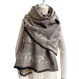 Brown and beige paisley cashmere shawl with elegant fringe hanging on a white model