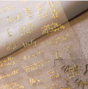 Macro detail of 3D embossed gold foil butterfly nail art stickers with cursive typography