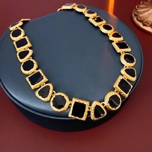 Detailed macro view of vintage geometric gold-tone necklace with black enamel inlay links