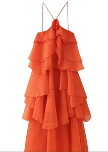 Détail de robe orange dos nu avec volants superposés et décoration florale en relief