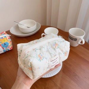 Quilted floral makeup bag with orange and blue flowers and white zipper closure