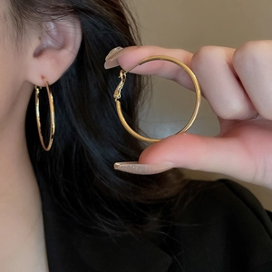 Detail of minimalist gold hoop earring featuring high-shine finish on model and in hand