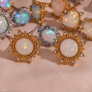 Macro detail of gold opal earrings with zircon stones on a pink silk background