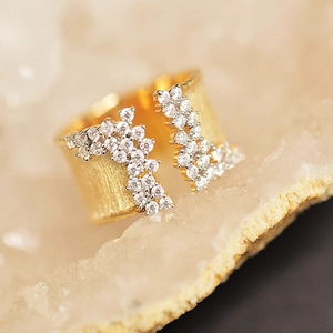 Macro shot of gold bypass ring with brushed texture and micro-pave cubic zirconia crystals