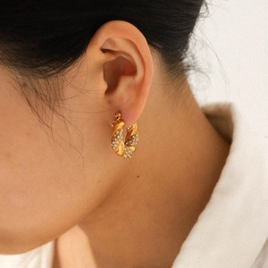 Detail of 18K gold plated twisted hoop earrings with shimmering rhinestones on ear