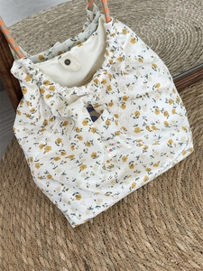 Detail of floral canvas bag with orange rope handles and drawstring closure on mat