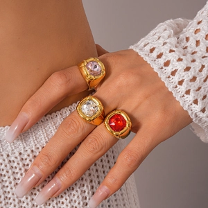 Macro detail of three vintage gold rings featuring red, pink, and white square gemstones