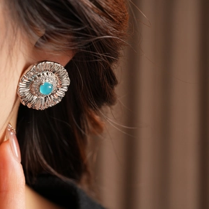 Close-up of vintage flower earrings with sky blue stone and zircon on female model