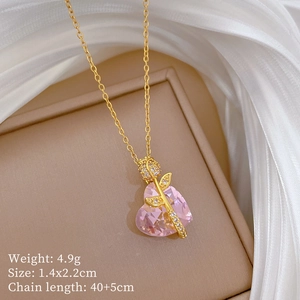 Macro shot of gold necklace with pink heart gem and diamond rose pendant detail