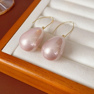 Dettaglio di orecchini a goccia con perle rosa e ganci dorati in una scatola portagioie