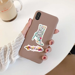 Close-up of inspirational quote stickers on a brown phone case with a clean desk background