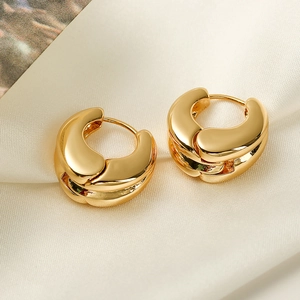 Polished gold plated irregular geometric hoop earrings on soft white silk background