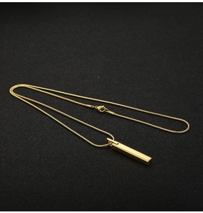 Macro shot of a golden rectangular bar pendant with sleek snake chain on black backdrop