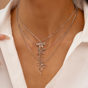 Collier argenté à trois rangs avec pendentifs nœuds porté par un mannequin en gros plan