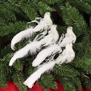 Close-up of white feathered bird Christmas ornaments with silver glitter on pine branches