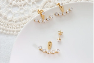 Detail of 18k gold plated stud earrings with a curved cubic zirconia jacket setting