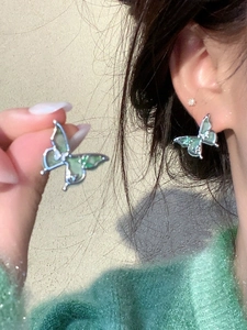 Gros plan de boucles d'oreilles papillon vert clair avec tiges en argent sur modèle