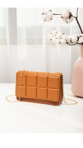 Detail of caramel quilted crossbody bag with gold chain strap and floral decor