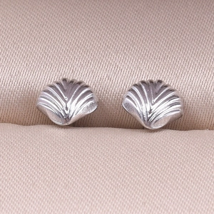 Macro shot of silver seashell stud earrings with realistic textured radial patterns