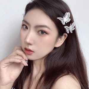 Detailed view of two white embroidered lace butterfly hair clips on model's hair