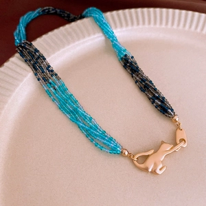 Detail of multi-strand beaded necklace with blue crystal beads and golden cat clasp