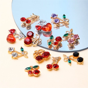 Detailed view of colorful cherry charms for DIY jewelry with rhinestones and metal rings