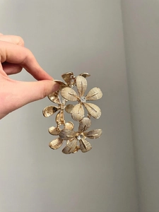 Detail of a gold flower bracelet with textured petals and inlaid clear rhinestones