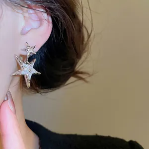 Minimalist silver star drop earrings with sparkling zircon crystals on female model