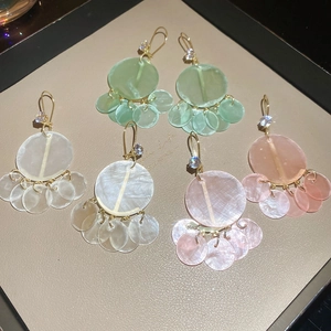Detail view of geometric shell petal drop earrings in green white and pink finishes