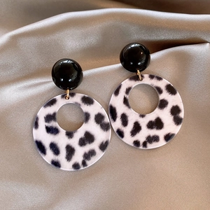 Acrylic leopard print hollow round pendant earrings on golden satin fabric background
