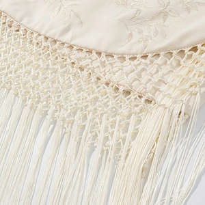 Vue détaillée de dentelle brodée florale beige avec pompons à franges décoratifs
