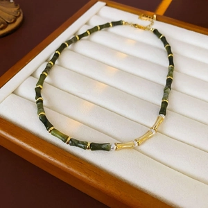 Detailed view of bamboo style stone necklace with gold beads and pearls on velvet