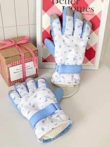 Macro view of blue floral ski gloves with touch screen tips and windproof ribbed cuffs