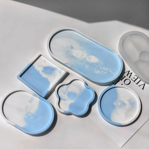 Flat lay of oval and floral resin coasters with blue marble texture and silicone molds