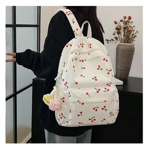 Detail of white corduroy backpack with cherry pattern and heart pompom keychain