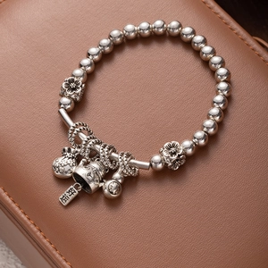Detail of silver beaded bracelet with fortune cat and flower charms on leather