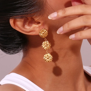 Detail of triple gold daisy drop earrings showing vertical floral cascade on model