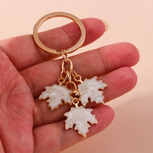 Detail of golden maple leaf keychain with white marble texture pendants on pink background