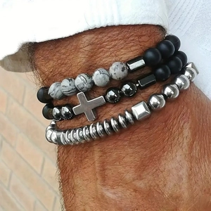 Close-up of a three-piece vintage bead bracelet set with silver cross pendant on wrist
