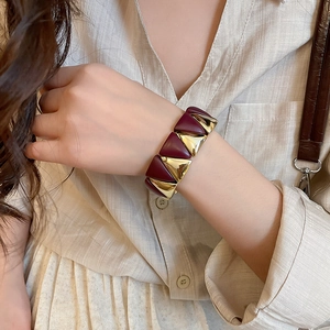 Close-up of geometric elastic bracelet with gold and burgundy triangles on a wrist