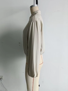 Side view of beige stand collar bomber jacket with pleated hem and elastic cuffs