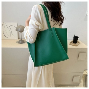 Close-up of a green large-capacity leather tote bag being carried by a model